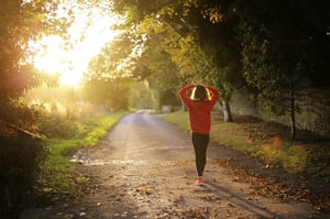 Woman walking down a road during sunset